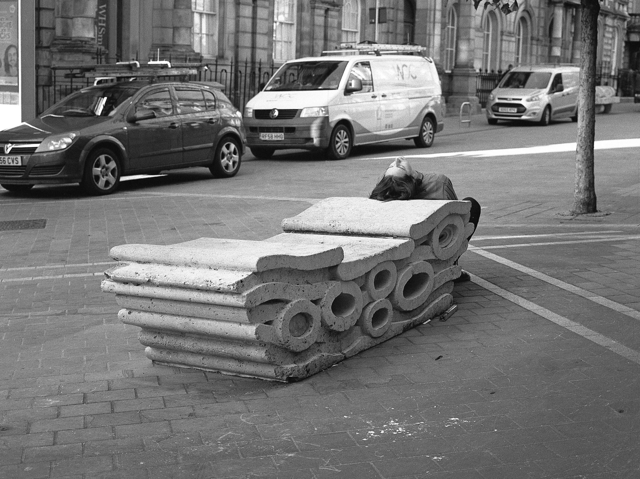 A black and white photograph of a concrete structure with a person laying on top of it