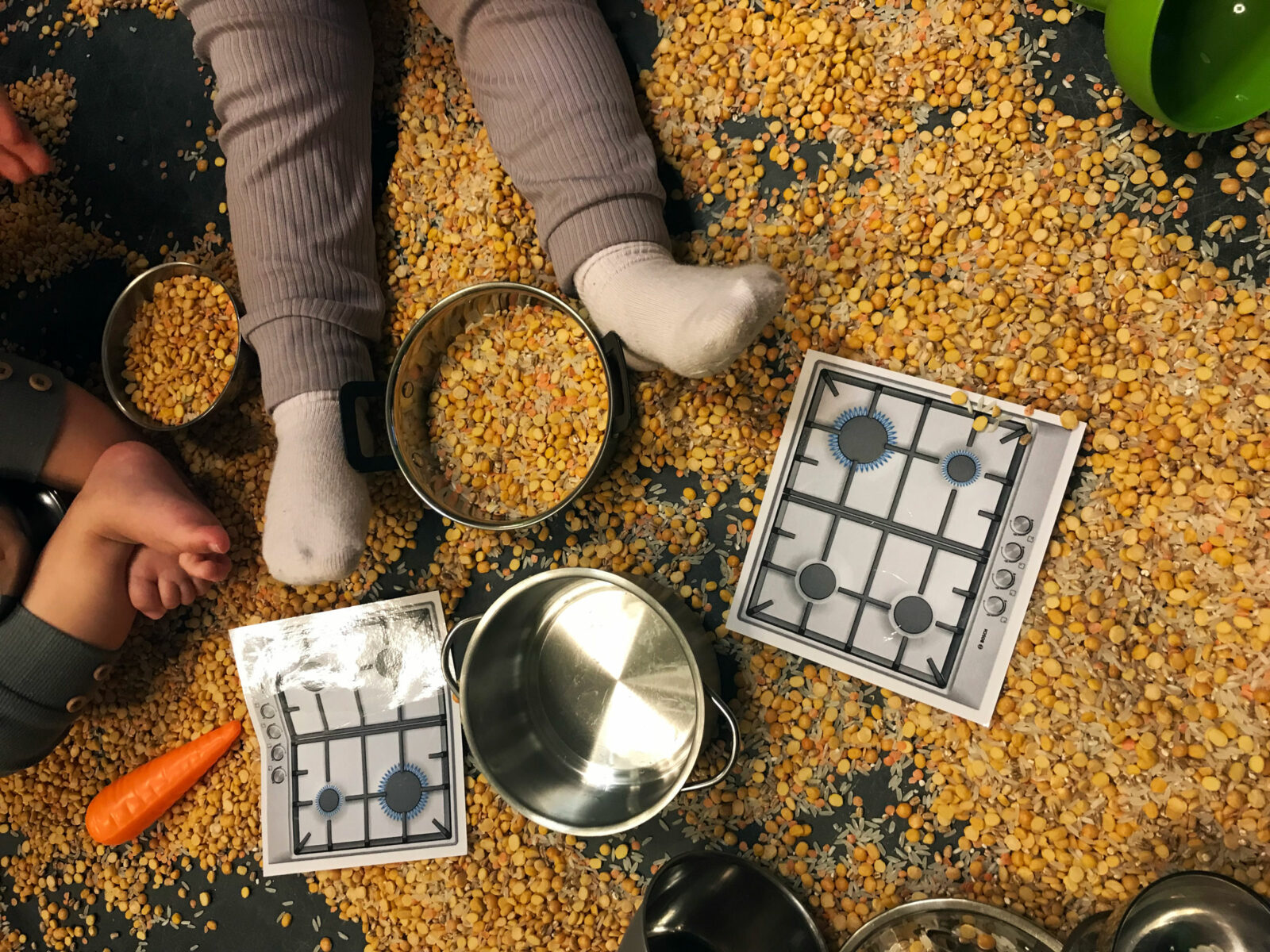 Baby's feet visible in a messy play environment with lentils